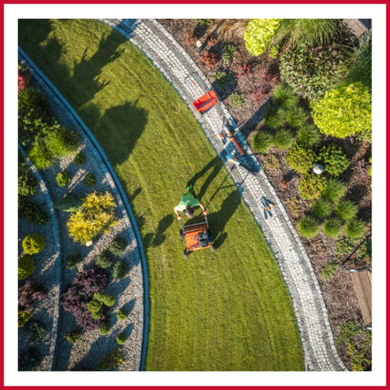 Landscaping RentalsAerial view of a person mowing a lush green lawn, bordered by colorful landscaped gardens. Sunlight casts long shadows, conveying a peaceful, sunny day.